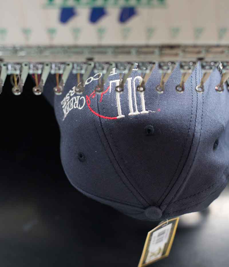 Navy blue cap getting embroidered on a machine