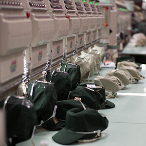 Production line of embroidery machines with hats resting on the counter
