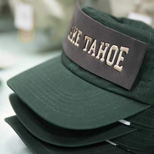 Stacked green hats with Lake Tahoe being added to the front